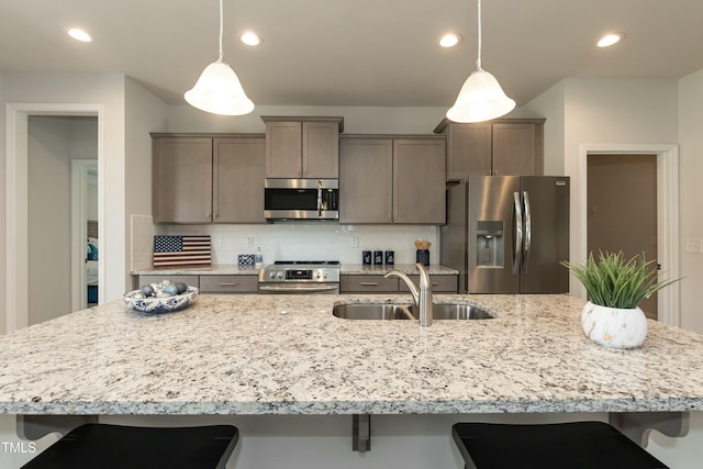 kitchen featuring backsplash, sink, decorative light fixtures, and appliances with stainless steel finishes