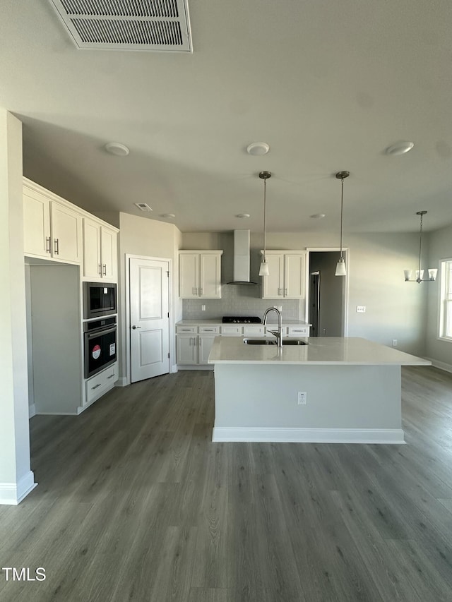 kitchen featuring wall chimney exhaust hood, oven, a sink, built in microwave, and white cabinetry