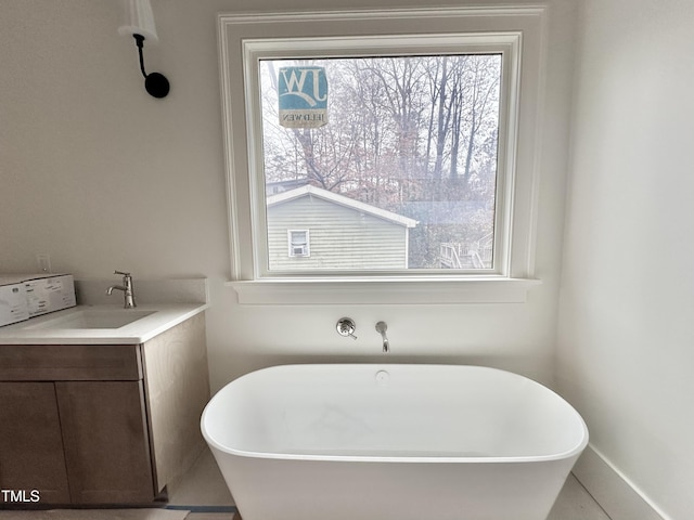 bathroom featuring a wealth of natural light, a tub to relax in, and vanity