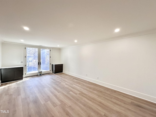 unfurnished living room featuring light hardwood / wood-style flooring, ornamental molding, and french doors