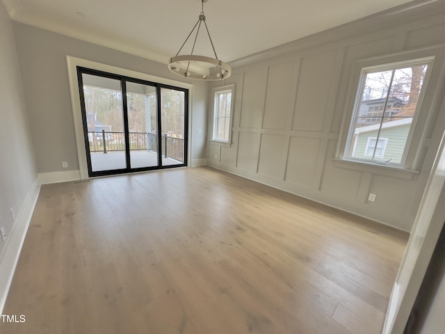 unfurnished room featuring light hardwood / wood-style floors, crown molding, and a chandelier