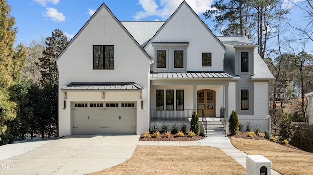 view of front facade with a standing seam roof, covered porch, brick siding, and concrete driveway