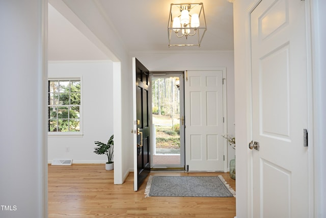 entrance foyer with a wealth of natural light, crown molding, and a notable chandelier