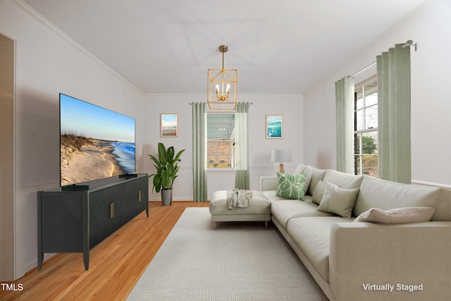 living room featuring wood-type flooring, crown molding, and a notable chandelier