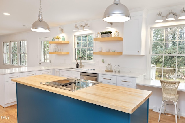 kitchen with sink, hanging light fixtures, butcher block countertops, a kitchen island, and white cabinetry