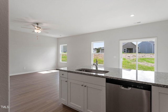 kitchen featuring dark wood-type flooring, white cabinets, sink, stainless steel dishwasher, and light stone countertops