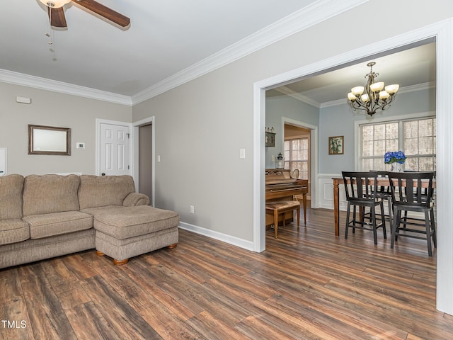 living room featuring baseboards, ornamental molding, dark wood-style flooring, and ceiling fan with notable chandelier