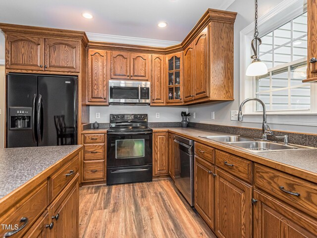 kitchen featuring dark countertops, black appliances, glass insert cabinets, and a sink