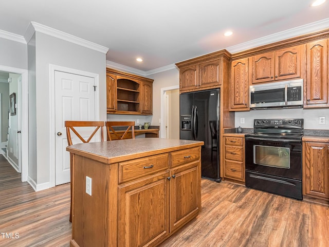 kitchen with black appliances, ornamental molding, a kitchen island, and brown cabinets