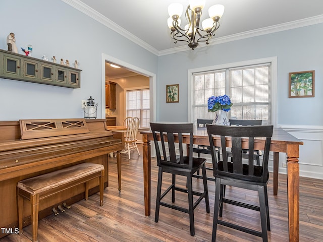 dining area with an inviting chandelier, ornamental molding, dark wood-style flooring, and wainscoting