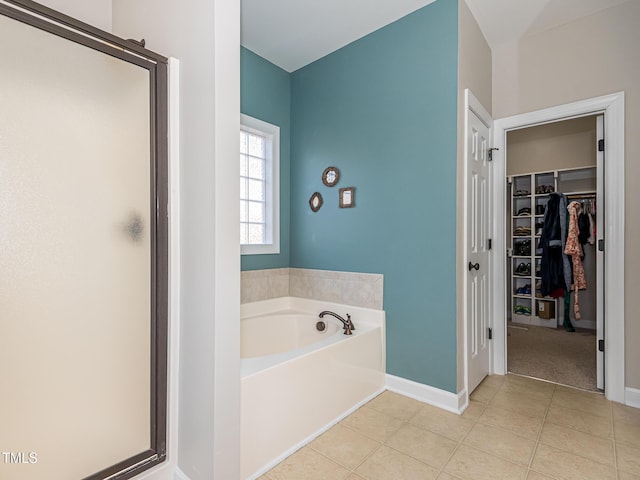 bathroom with a garden tub, tile patterned flooring, baseboards, a shower stall, and a walk in closet