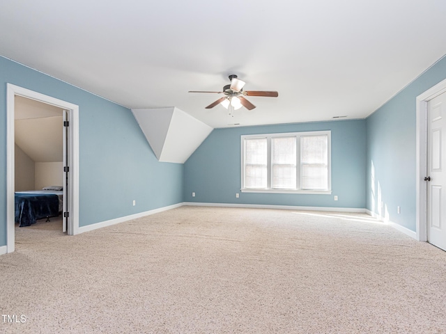 bonus room with a ceiling fan, light colored carpet, vaulted ceiling, and baseboards