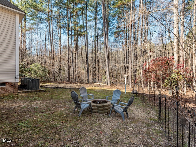 view of yard featuring central AC, fence, and a fire pit