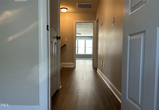 hallway featuring visible vents, dark wood finished floors, and baseboards