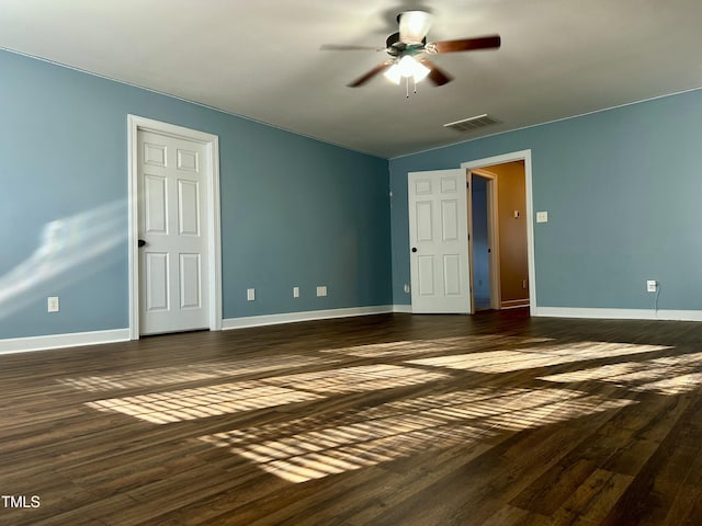 empty room featuring dark wood finished floors, visible vents, and baseboards