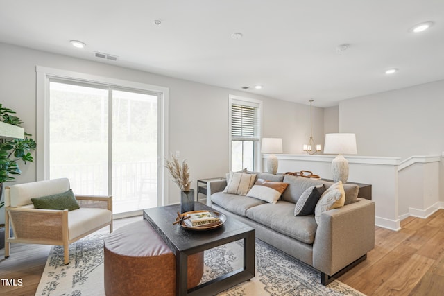 living room with a chandelier, light hardwood / wood-style flooring, and plenty of natural light