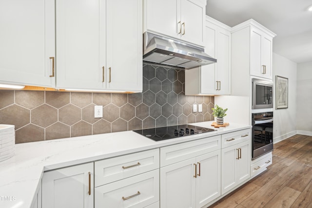 kitchen with wall oven, light hardwood / wood-style floors, light stone countertops, white cabinets, and black electric cooktop