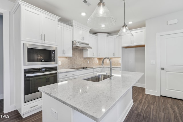 kitchen with a kitchen island with sink, sink, hanging light fixtures, and stainless steel oven