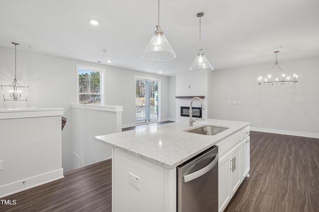 kitchen with pendant lighting, white cabinetry, sink, stainless steel dishwasher, and a center island with sink