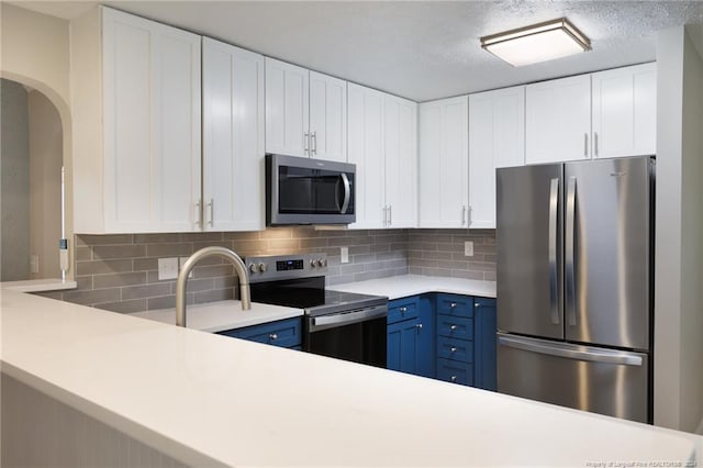 kitchen featuring decorative backsplash, appliances with stainless steel finishes, white cabinetry, and light countertops