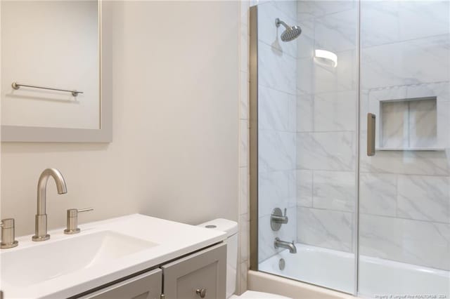 bathroom featuring toilet, vanity, and shower / bath combination with glass door