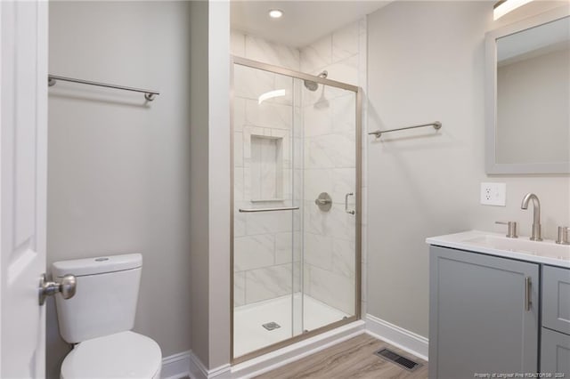 bathroom with visible vents, a shower stall, baseboards, toilet, and vanity