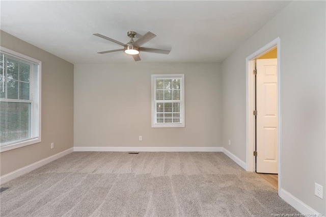 spare room featuring baseboards, light colored carpet, and a ceiling fan