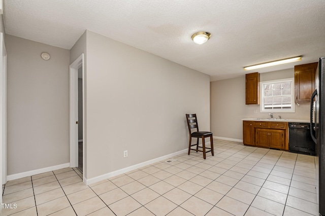 kitchen with a textured ceiling, dishwasher, light tile patterned floors, and sink