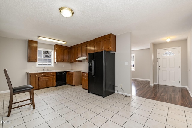 kitchen featuring black appliances, light hardwood / wood-style floors, sink, and a textured ceiling