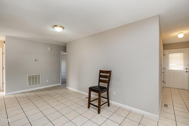 tiled empty room featuring a textured ceiling