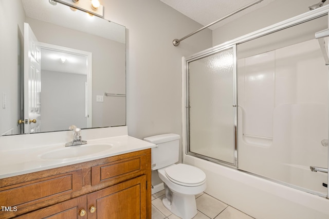 full bathroom with a textured ceiling, vanity, shower / bath combination with glass door, tile patterned flooring, and toilet