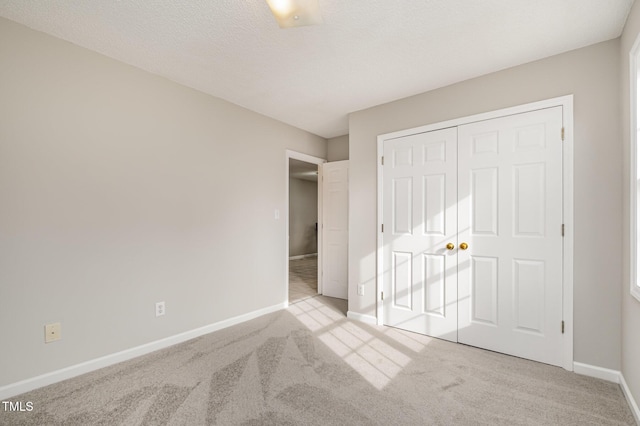 unfurnished bedroom with light carpet, a textured ceiling, and a closet