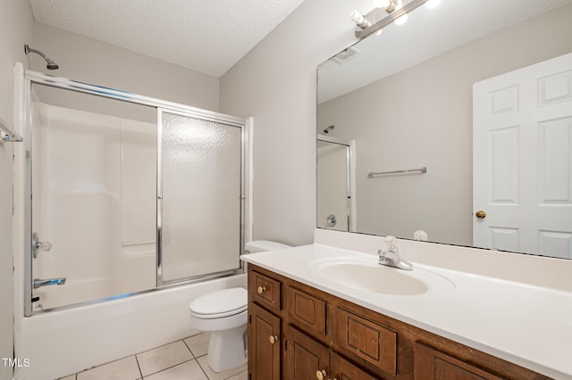 full bathroom with tile patterned flooring, combined bath / shower with glass door, a textured ceiling, toilet, and vanity