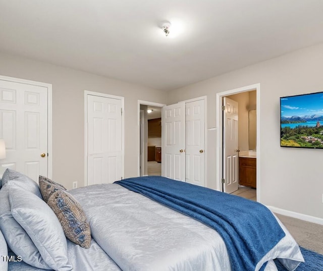 carpeted bedroom with ensuite bath and two closets