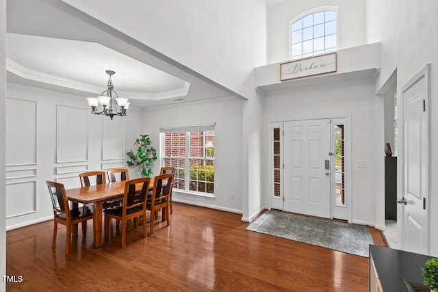 foyer with a chandelier, hardwood / wood-style floors, a tray ceiling, and crown molding