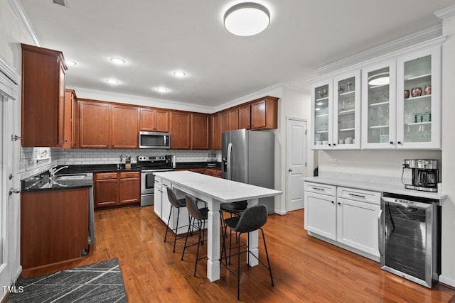 kitchen featuring stainless steel appliances, sink, white cabinetry, wine cooler, and a breakfast bar area