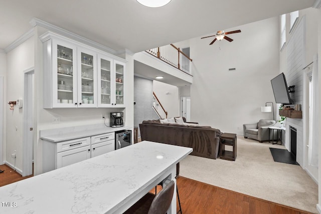 kitchen with white cabinetry, ceiling fan, beverage cooler, a kitchen breakfast bar, and dark carpet