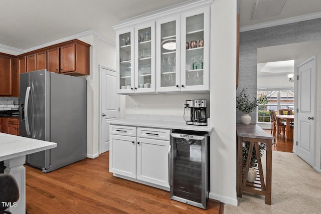 kitchen with light stone countertops, stainless steel refrigerator with ice dispenser, wine cooler, crown molding, and white cabinetry