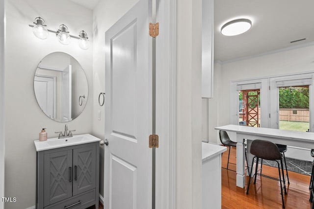 bathroom with hardwood / wood-style floors, vanity, and ornamental molding