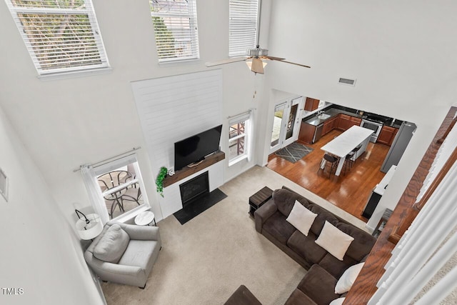 carpeted living room featuring ceiling fan and high vaulted ceiling