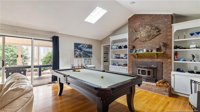 rec room with vaulted ceiling with skylight, light hardwood / wood-style floors, a wood stove, and pool table