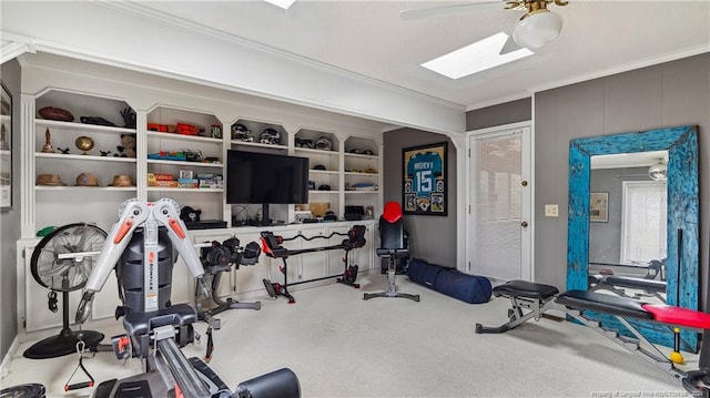 workout room with a skylight, ceiling fan, carpet floors, and ornamental molding