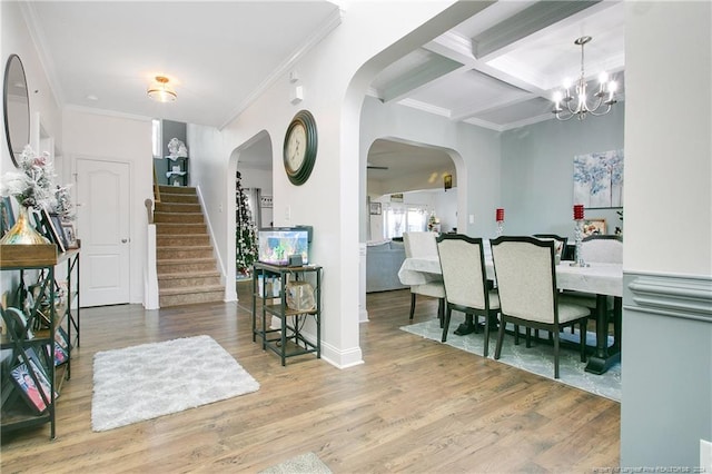 dining room featuring ornamental molding, a chandelier, coffered ceiling, and hardwood / wood-style flooring