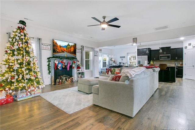 living room featuring dark hardwood / wood-style flooring, ceiling fan, and crown molding