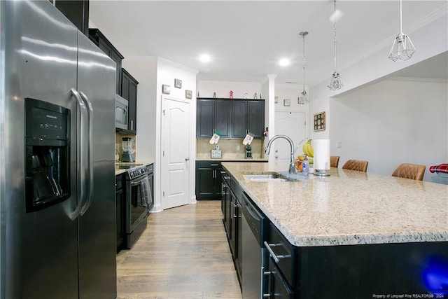 kitchen featuring pendant lighting, hardwood / wood-style floors, a kitchen island with sink, sink, and stainless steel appliances