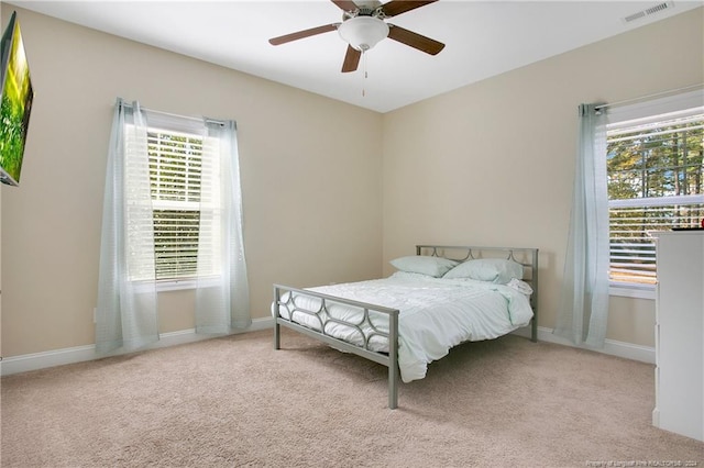 bedroom featuring light carpet, multiple windows, and ceiling fan