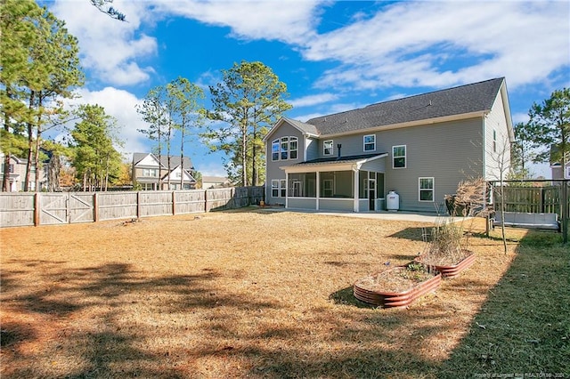 rear view of property with a sunroom, a patio area, and a lawn