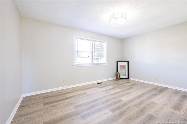 spare room featuring a textured ceiling and light wood-type flooring