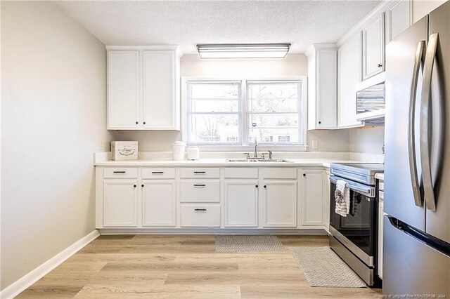 kitchen with a textured ceiling, stainless steel appliances, sink, white cabinets, and light hardwood / wood-style floors