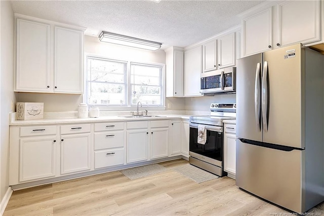 kitchen featuring white cabinets, stainless steel appliances, light hardwood / wood-style floors, and sink